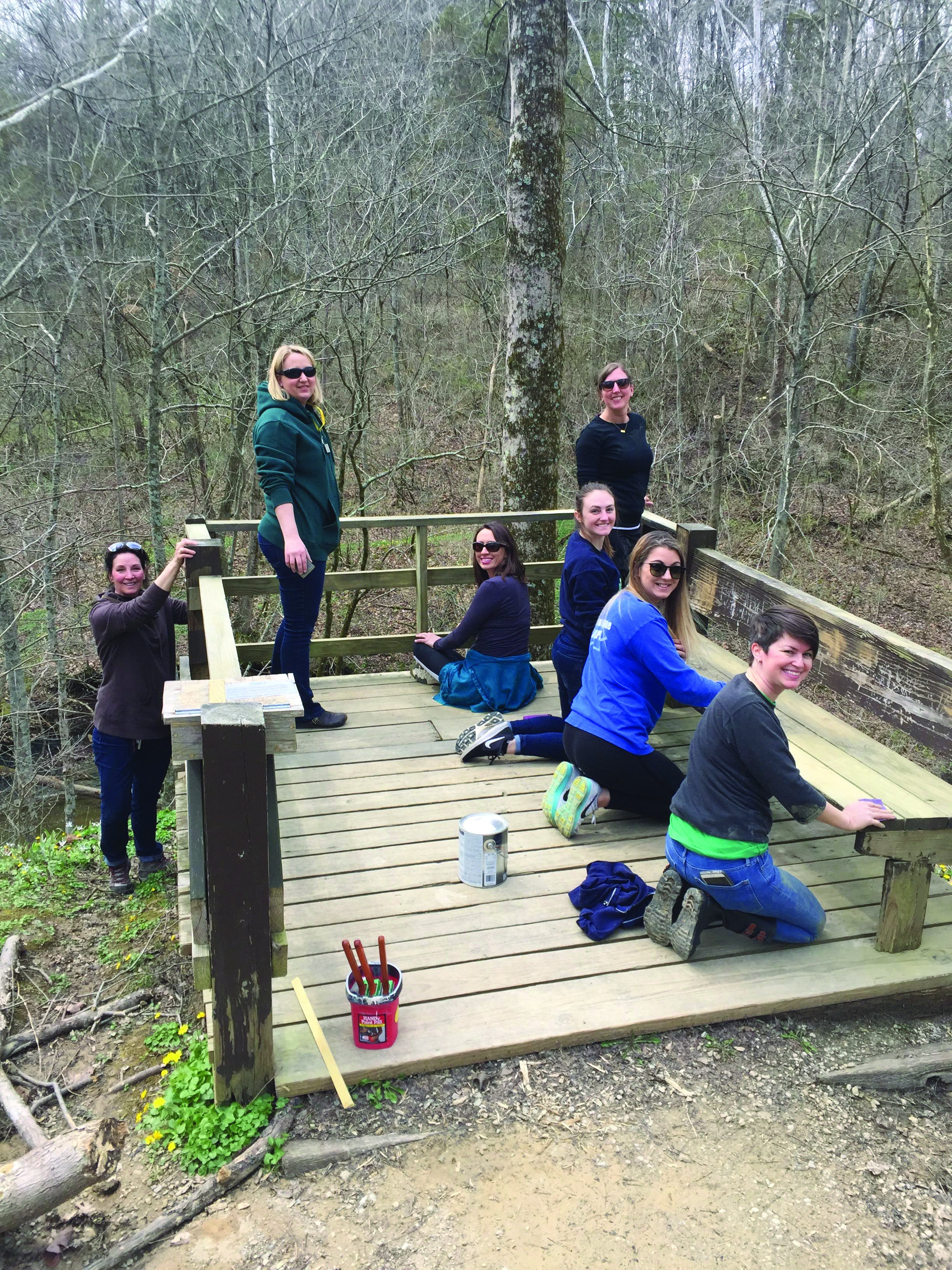 A group of young white women working on a wooden deck overlook