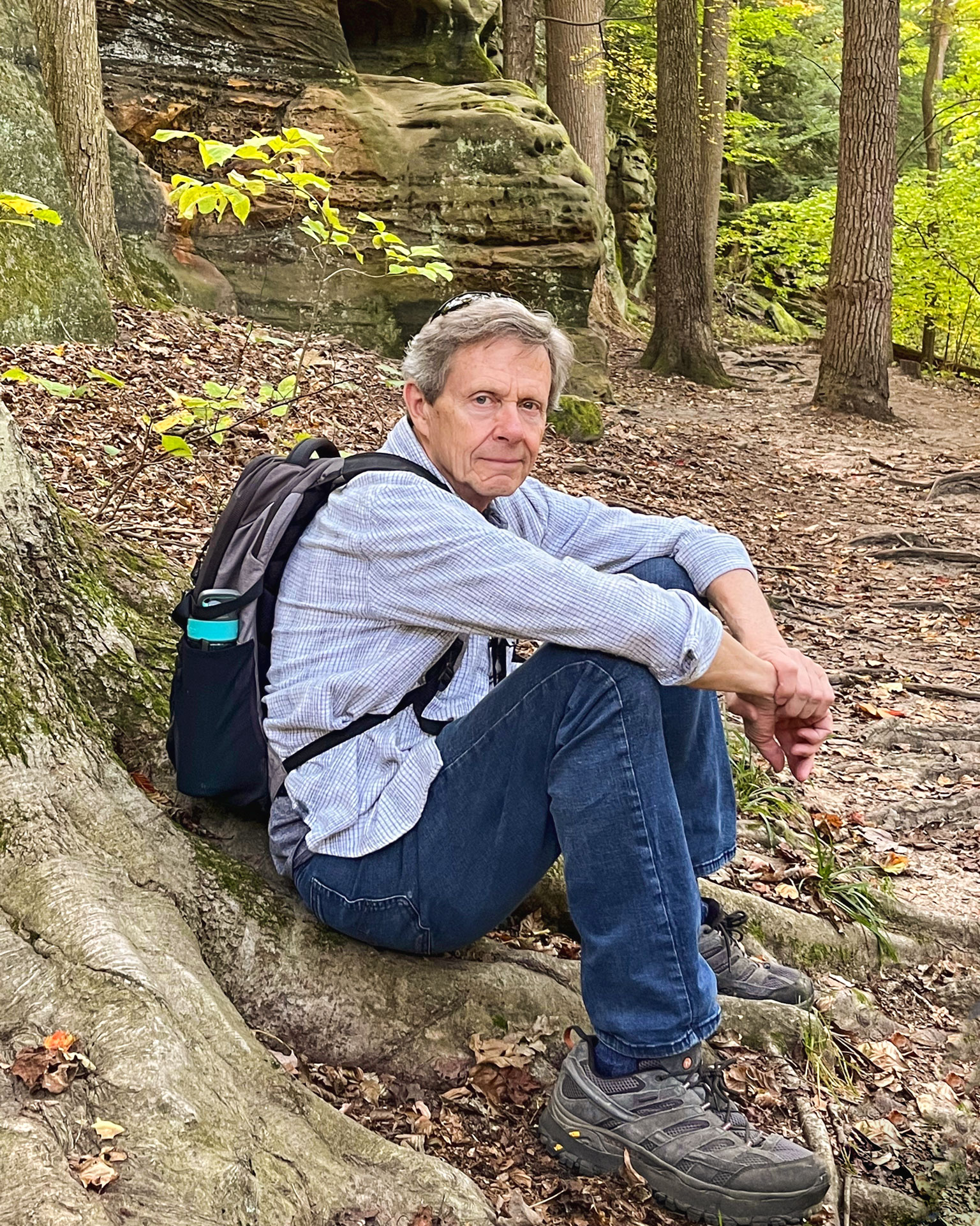 Bob Rack sits on the base of a tree in beautiful autumn gorge habitat.