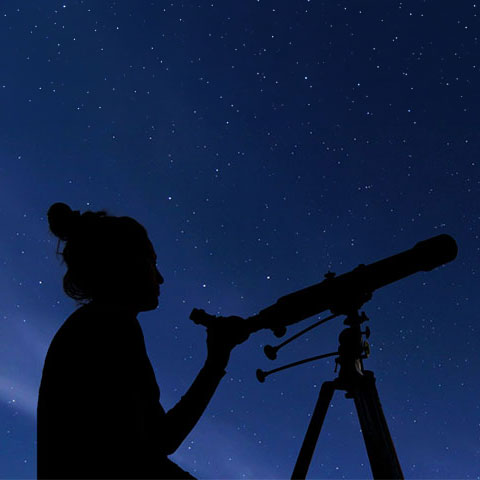 Girl with telescope under stary night sky.